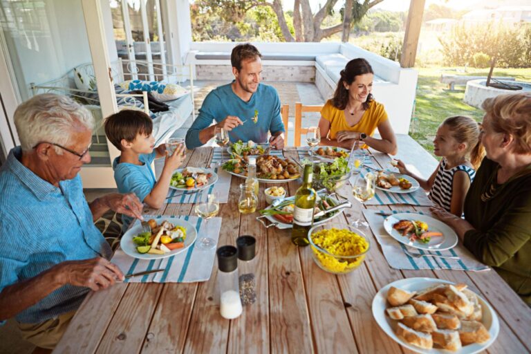 A large family of several generations, sitting at a table enjoying a meal together.